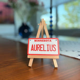 Personalized mini license plate displayed on wooden tripod stand for product presentation