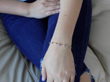 Multicolor evil eye bracelet held in a hand to show scale and detail of the tiny nazar charms.